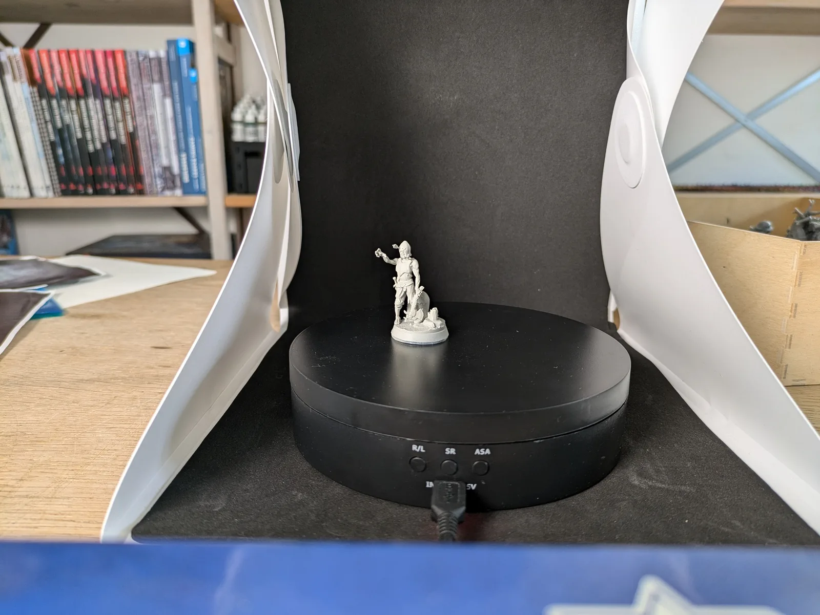 Single grey resin armoured female miniature in dynamic pose on a turntable, freshly printed at 50 microns