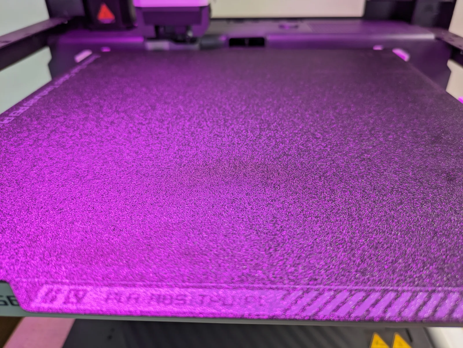 Close-up of a Bambu textured PEI build plate, sandpaper-like surface and PLA / ABS / TPU label visible