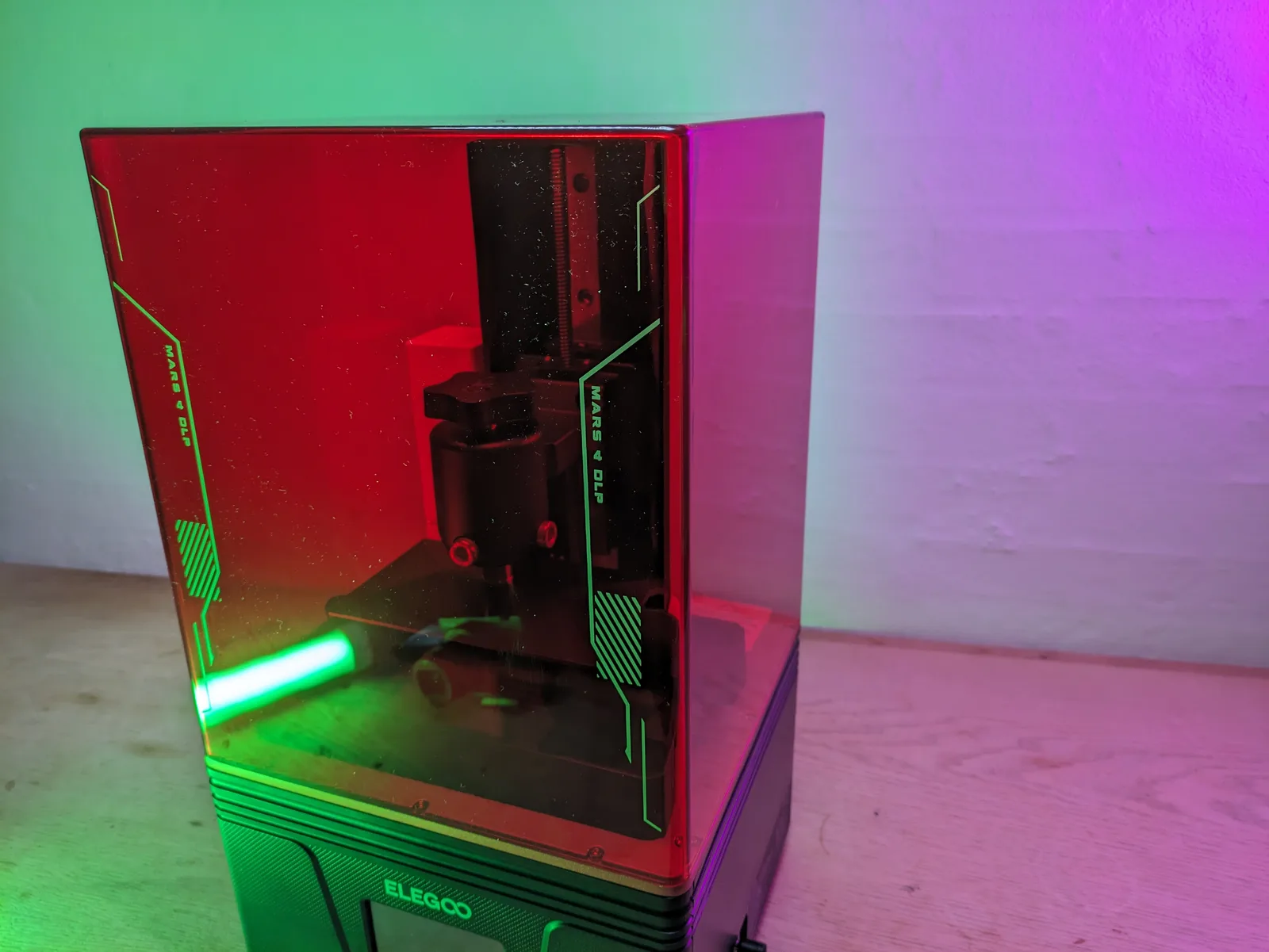 Elegoo Mars 4 DLP front view with red tinted acrylic hood and dramatic green and purple RGB accent lighting