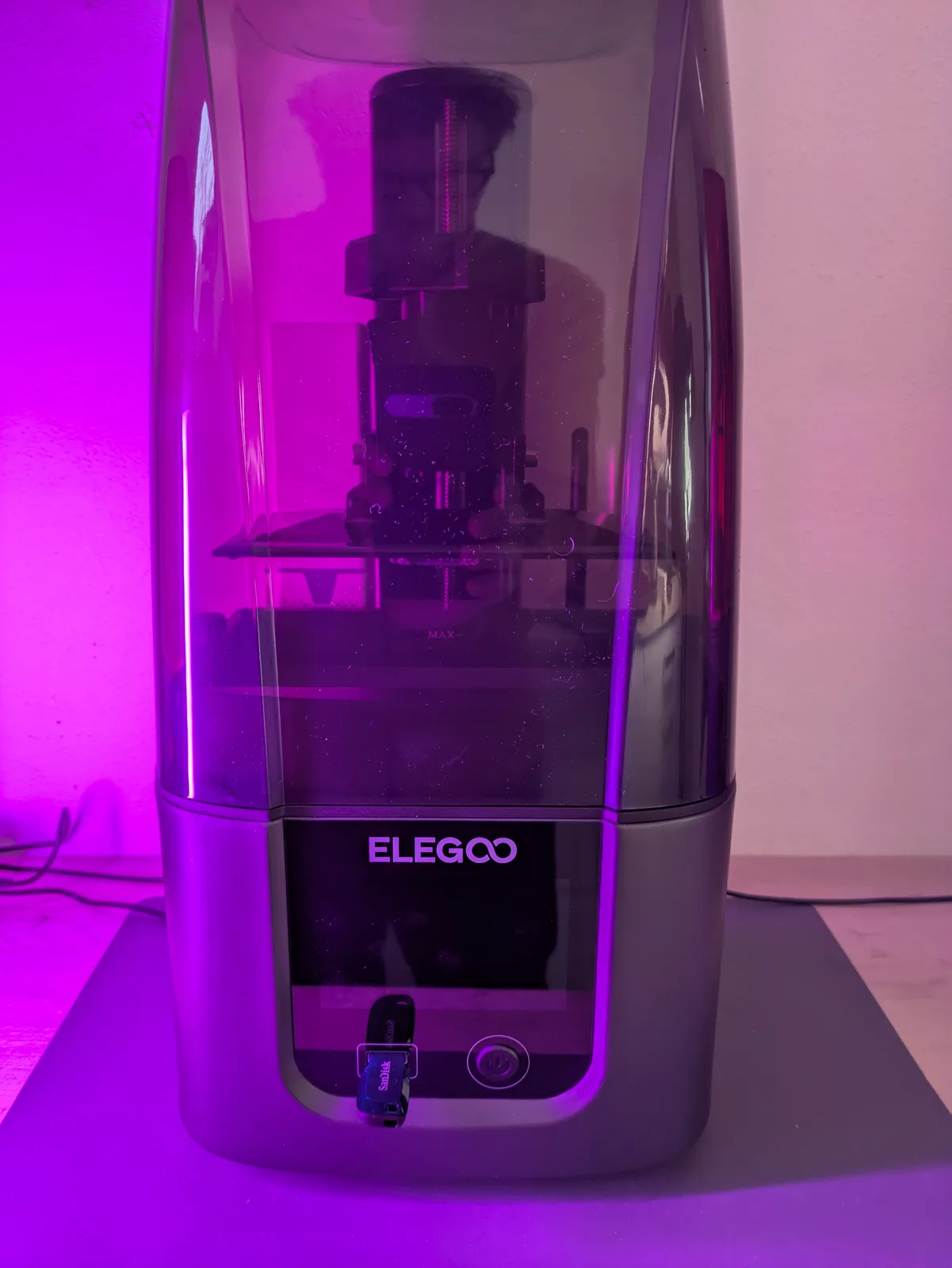 Elegoo Saturn 4 Ultra front view, smoked cylindrical acrylic cover with dual linear rails visible inside, purple ambient lighting