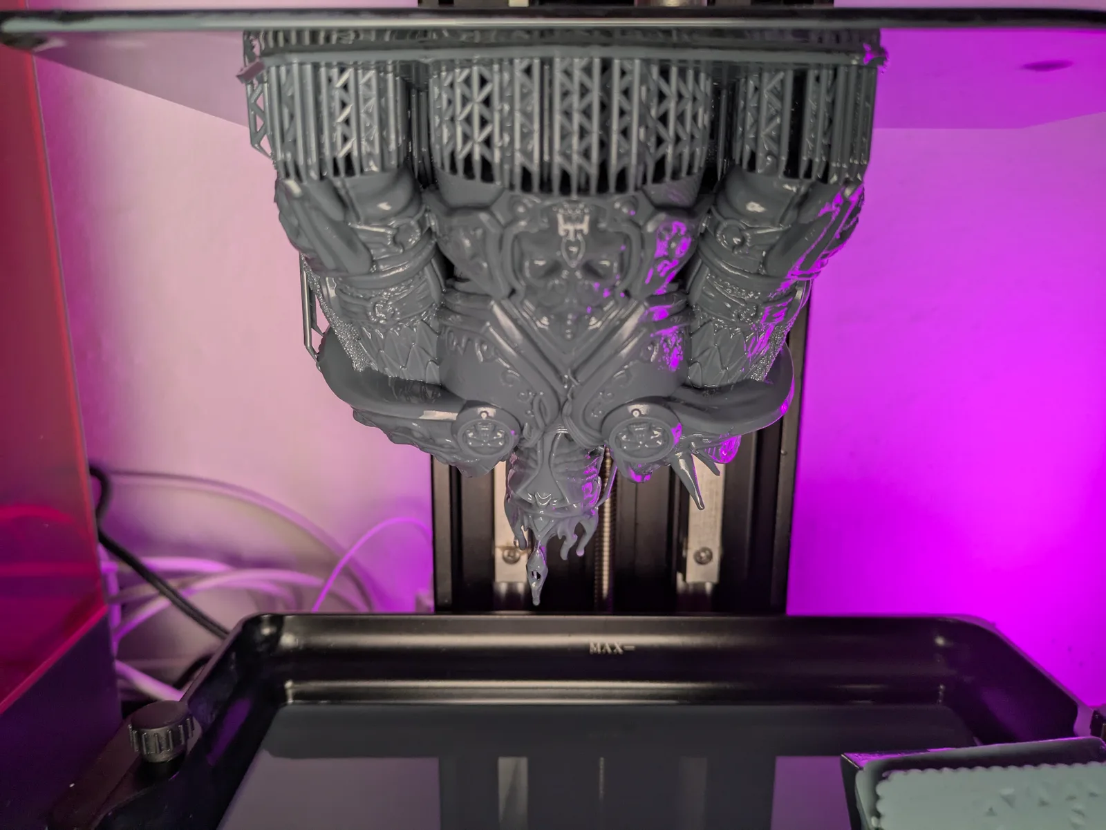 Saturn 4 Ultra build plate fully raised showing a large Lich King throne group print hanging upside down, three heavily armoured figures flanking a central ornate throne, dense lattice supports across the top, wet resin visible, purple ambient glow